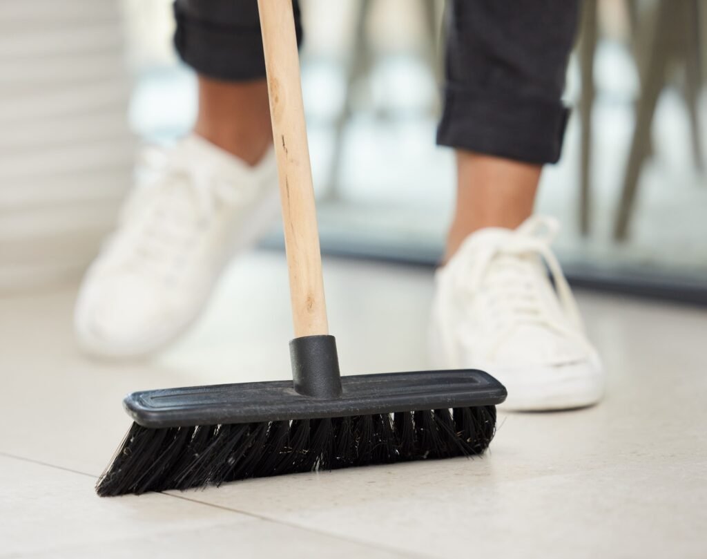 Enfonce le nouveau balai. Photo recadrée d'une femme méconnaissable utilisant un balai pour balayer sa maison.-min